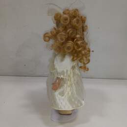 Porcelain doll, blonde, white dress, on stand alternative image