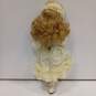 Dynasty Doll Collection Porcelain (Music Box Inside) Doll With Blonde Curly Hair, Blue Eyes, And Yellow Outfit image number 2