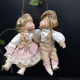 Porcelain Dolls Swinging in Wall Hanging Chair alternative image
