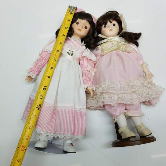 Lot of 2 vintage porcelain brown hair dolls in pink outfits image number 3