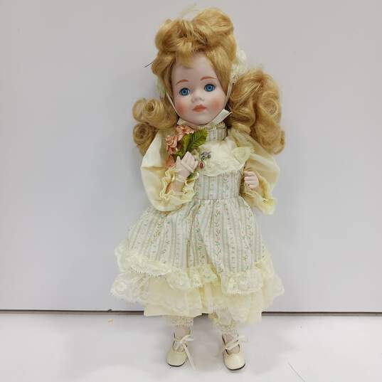 Dynasty Doll Collection Porcelain (Music Box Inside) Doll With Blonde Curly Hair, Blue Eyes, And Yellow Outfit image number 1