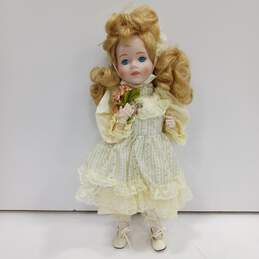 Dynasty Doll Collection Porcelain (Music Box Inside) Doll With Blonde Curly Hair, Blue Eyes, And Yellow Outfit