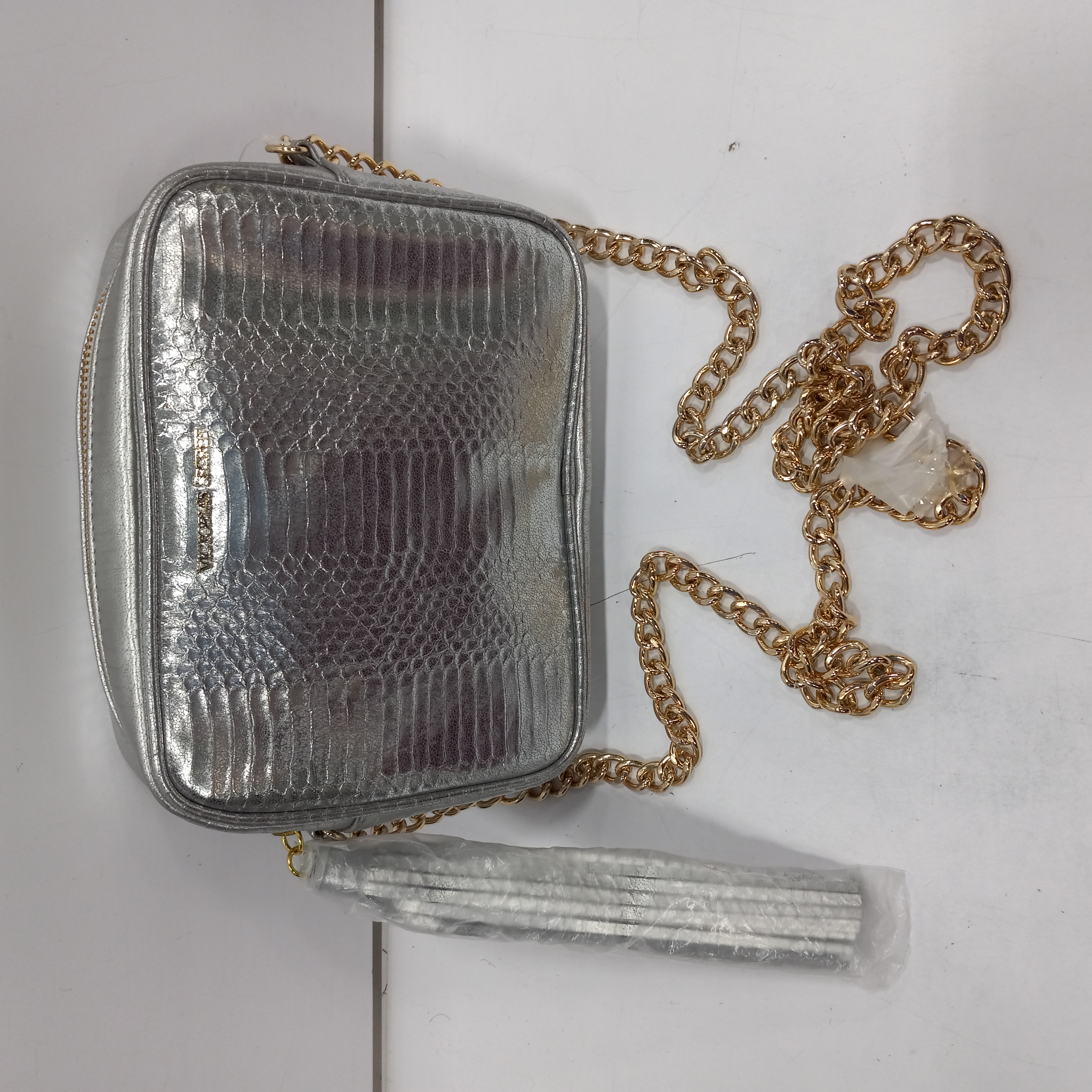 Buy the Victoria's Secret Silver Crossbody Clutch Bag with Gold Chain Strap  and Tassel Zipper Pull